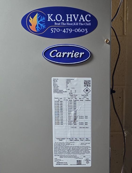 The rating plate on a Carrier air handler, under a KO HVAC label and the Carrier badge