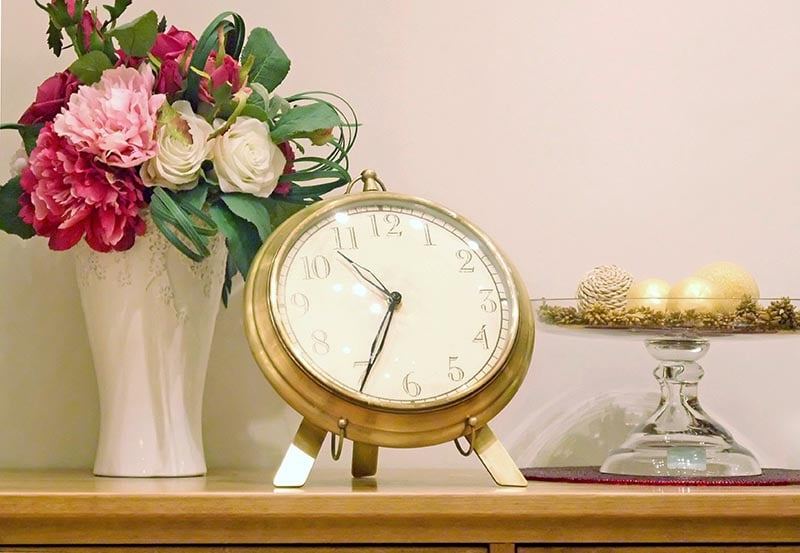 Clock and vase are on the shelf.