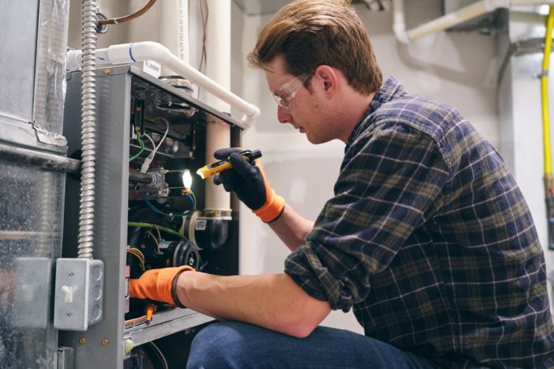7 Furnace Maintenance Tips. Tech in front of furnace.