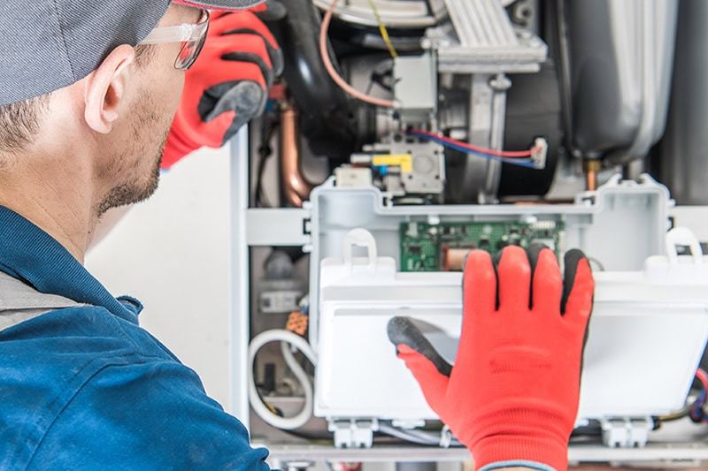 How Can I Make My Furnace Last Longer? Photo of a technician inspecting a furnace.
