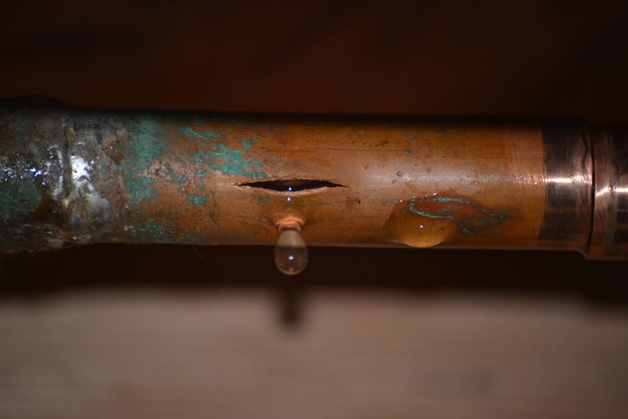 close-up image of a cracked, leaking water pipe.