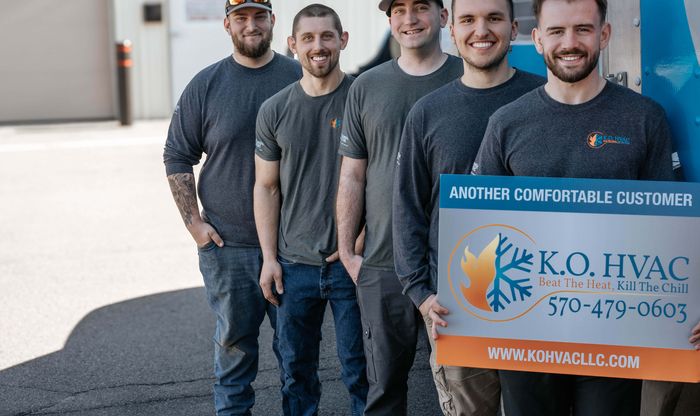Five KO HVAC technicians holding a KO HVAC yard sign in front of the box truck