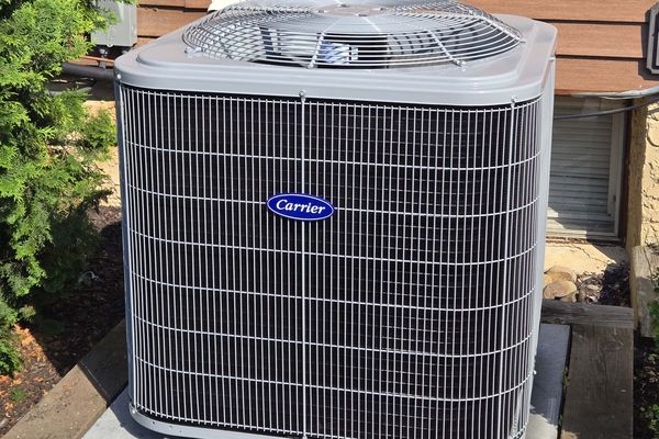 A new Carrier condenser on a block pad against cedar siding