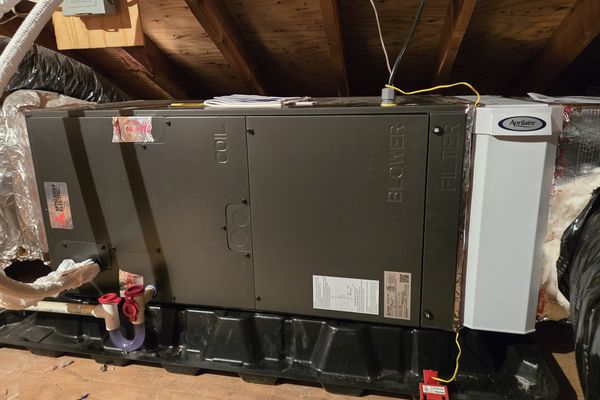 A horizontal air handler hung in an attic with duct connections