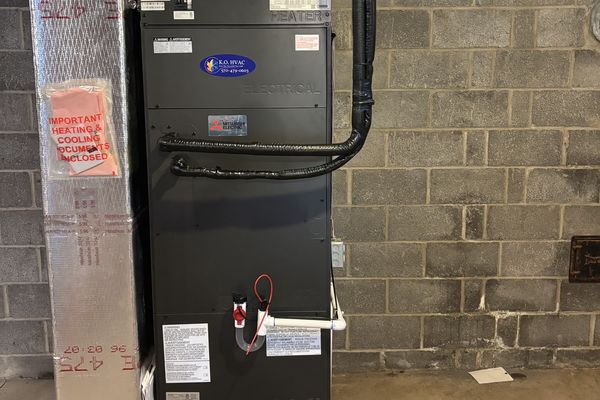 A black air handler against a block wall