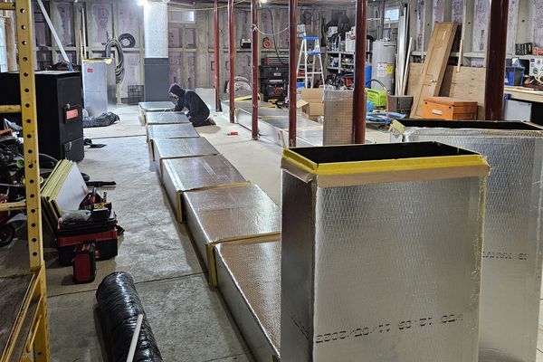 A long run of new insulated sheet-metal ductwork in a large basement