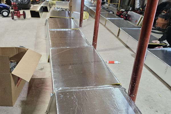 New insulated rectangular duct sections being installed along a basement