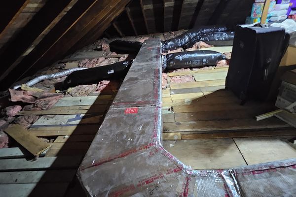 An insulated duct trunk with elbows running across an attic floor