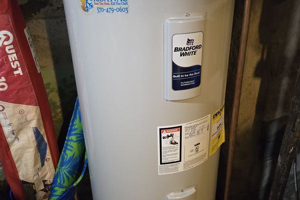 A Bradford White water heater with a KO HVAC sticker in a basement
