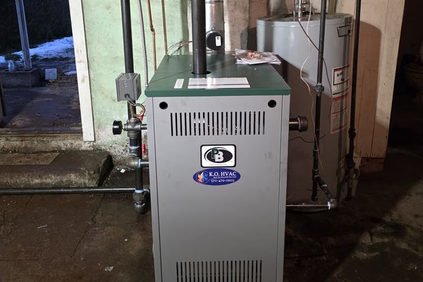 A gas boiler with a KO HVAC sticker in a basement