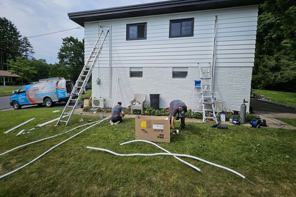 Two KO HVAC technicians at work on a front lawn, the KO van behind them