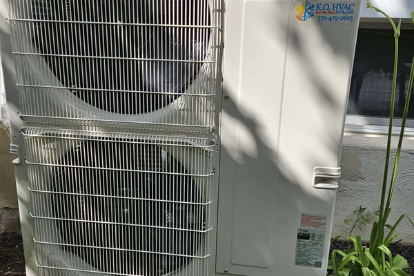 A two-fan Mitsubishi heat pump outdoor unit with a KO HVAC label