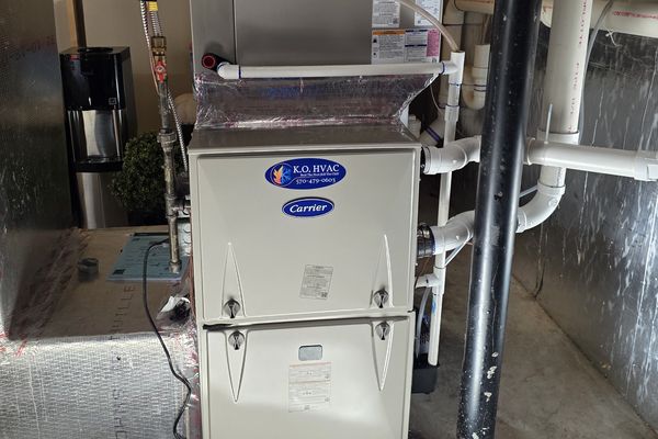 A Carrier furnace with a KO HVAC sticker in a basement