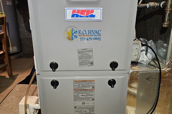 A gas furnace with a KO HVAC sticker in a basement