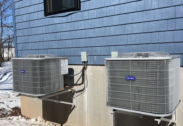 Two Carrier condensers mounted on wall brackets above the snow