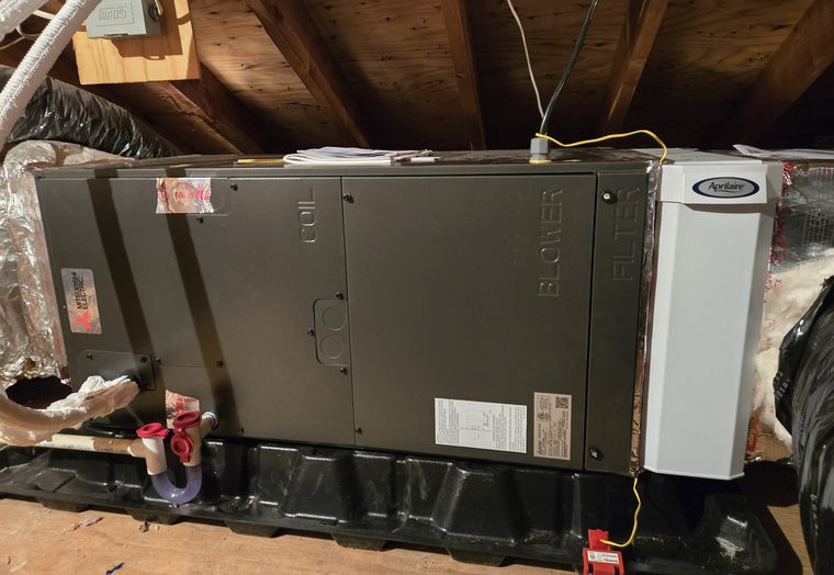 A horizontal air handler hung in an attic with duct connections