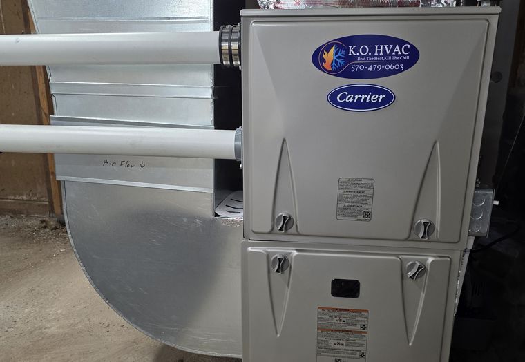 A Carrier furnace with a KO HVAC plate and new sheet-metal ductwork in a basement