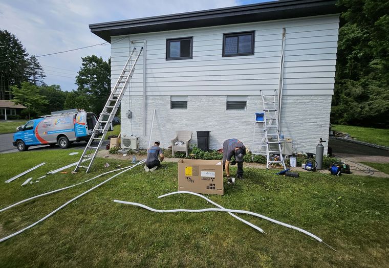 Two KO HVAC technicians at work on a front lawn, the KO van behind them