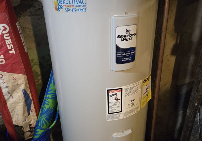 A Bradford White water heater with a KO HVAC sticker in a basement
