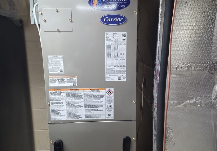A Carrier air handler with a KO HVAC plate in a closet, wrapped with foil-faced insulation