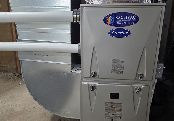 A Carrier furnace with a KO HVAC plate and new sheet-metal ductwork in a basement
