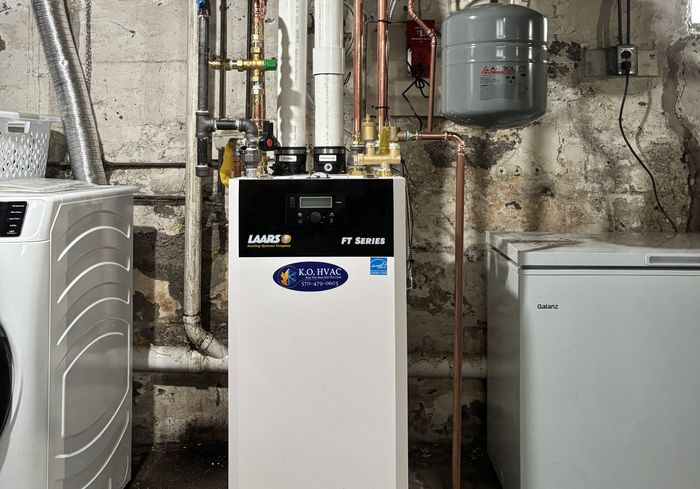 A white high-efficiency boiler with piping and an expansion tank
