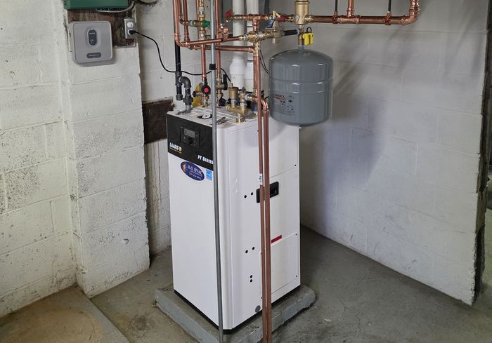 A white boiler with a copper manifold and an expansion tank