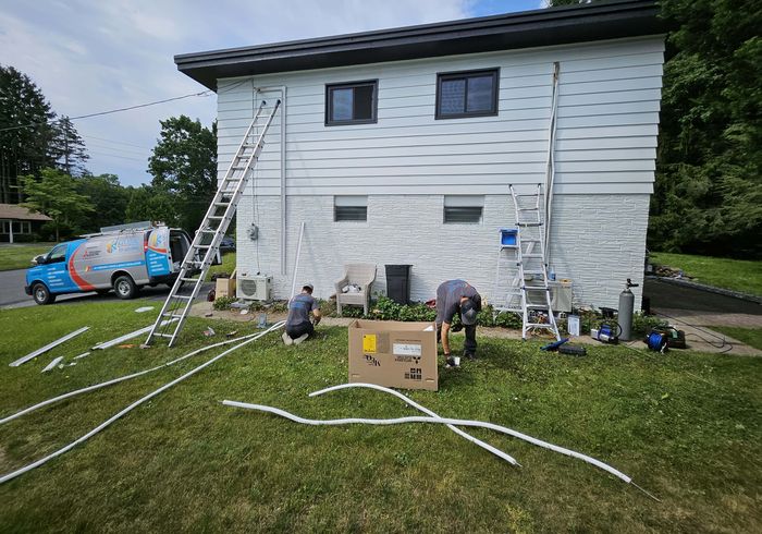 Two KO HVAC technicians at work on a front lawn, the KO van behind them