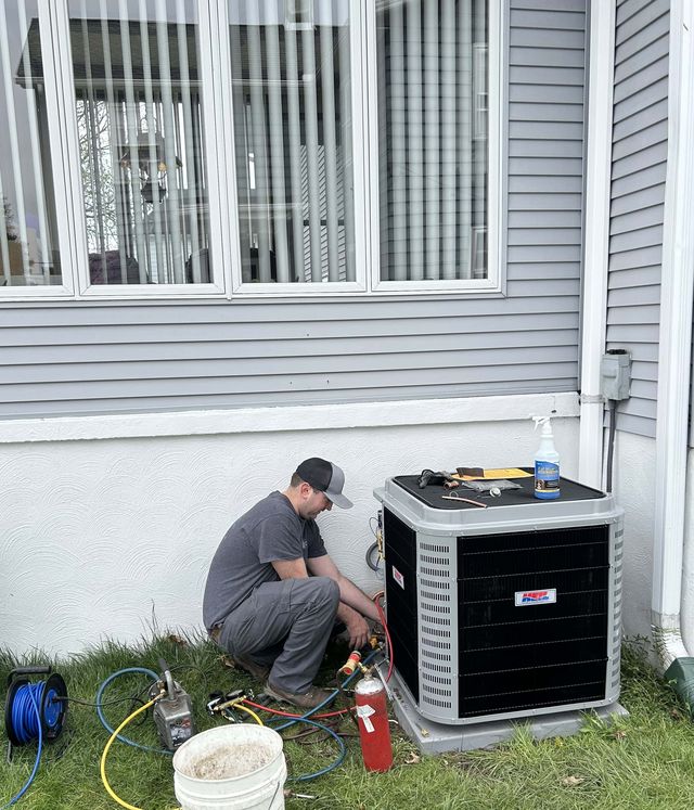 A KO HVAC technician testing an outdoor condenser with gauges connected