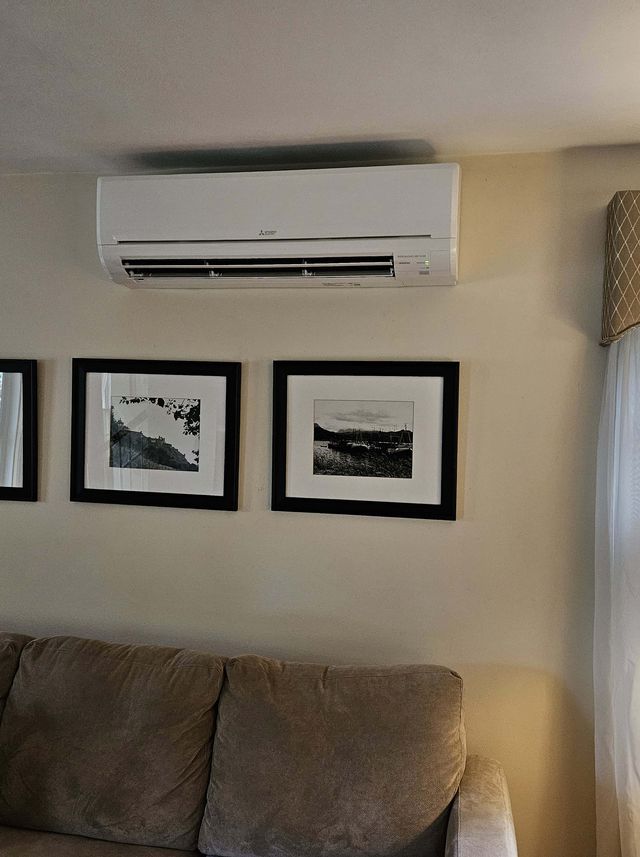 A Mitsubishi ductless unit installed above a living room sofa, the room left clean