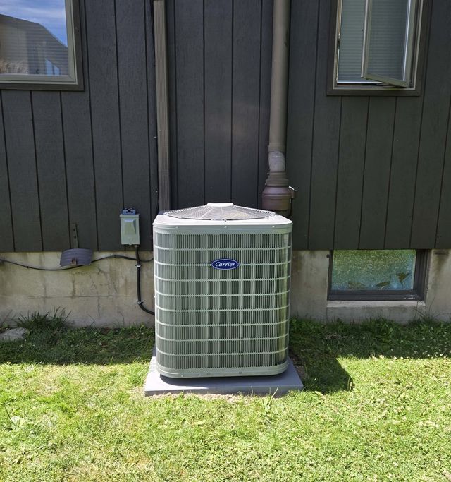 A new Carrier condenser installed on a pad beside a home