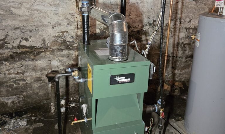 A green boiler in a stone-wall basement