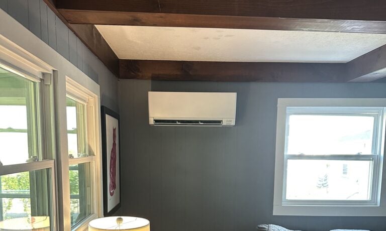 A Mitsubishi wall unit in a living room with a beamed ceiling